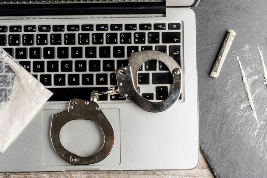 Handcuffs and illegal drugs on a laptop