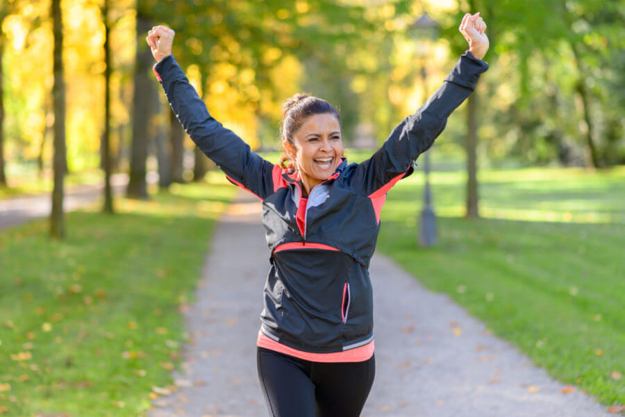 Woman victoriously walks outside, happy about successful treatment of autoimmune disease.