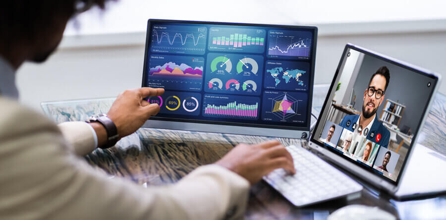 Person talking to outsourced, virtual accountant on Zoom while checking financial reports on another laptop.