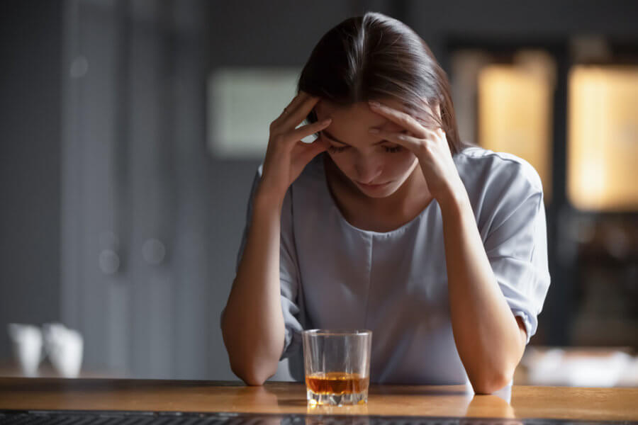 Sad woman self-medicating with alcohol
