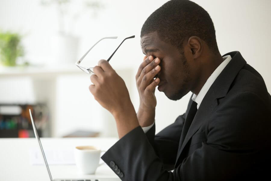 Businessman rubs his face trying to relieve chronic fatigue.