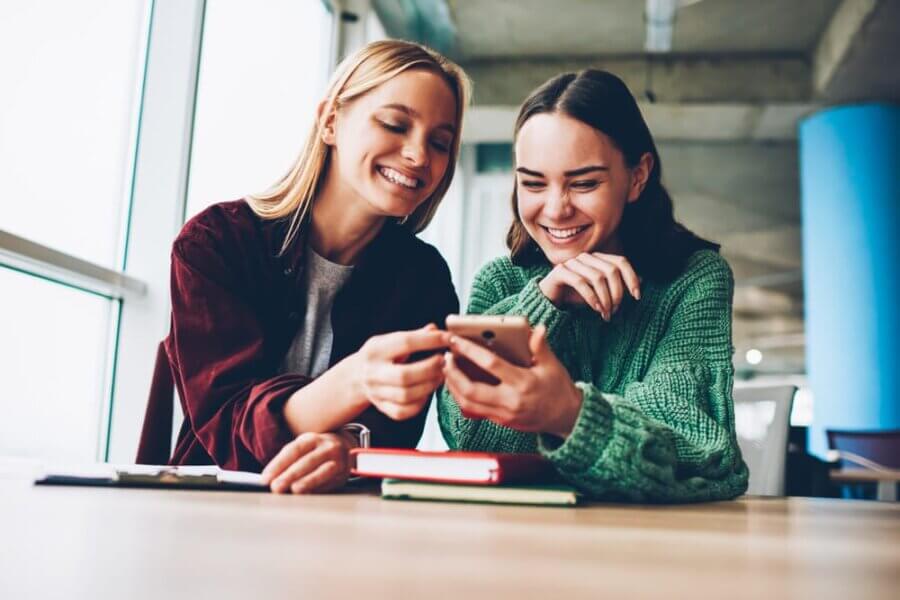 Two women check social media marketing for mental health clinic on phone