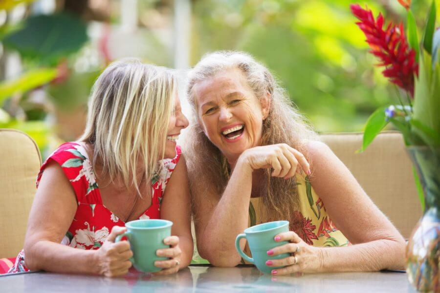 Two women laugh and drink coffee together, feeling energetic and relief from fatigue.