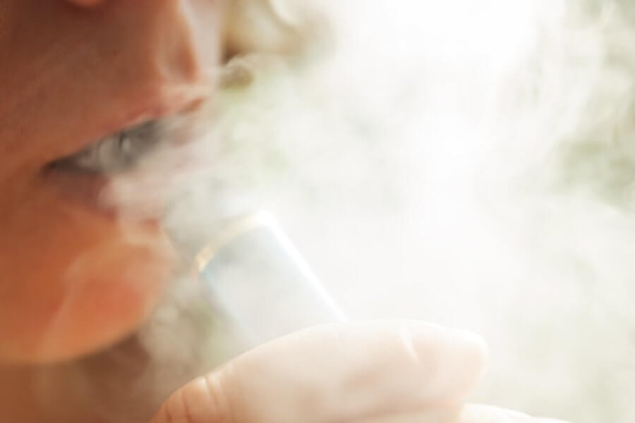 Woman harming her dental health by vaping